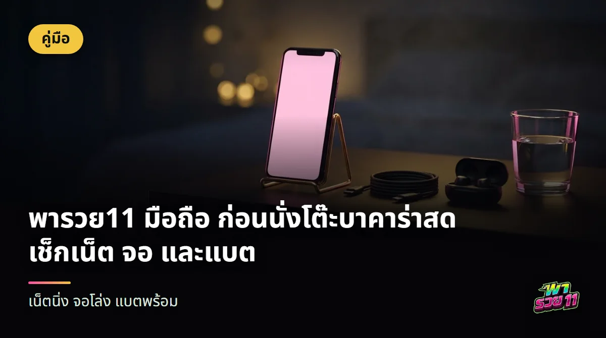 มือถือตั้งบนขาตั้งโลหะสีทอง ข้างกันมีสายชาร์จม้วนเก็บ หูฟังไร้สายในกล่อง และแก้วน้ำบนโต๊ะข้างเตียงยามค่ำ